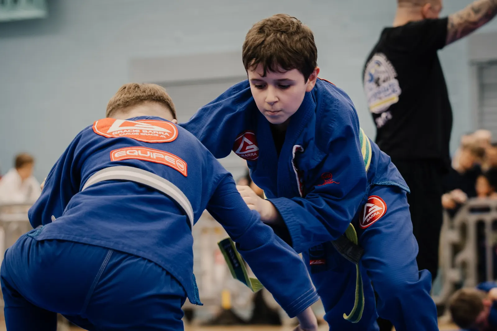 Two young students in blue gis practising standing grips