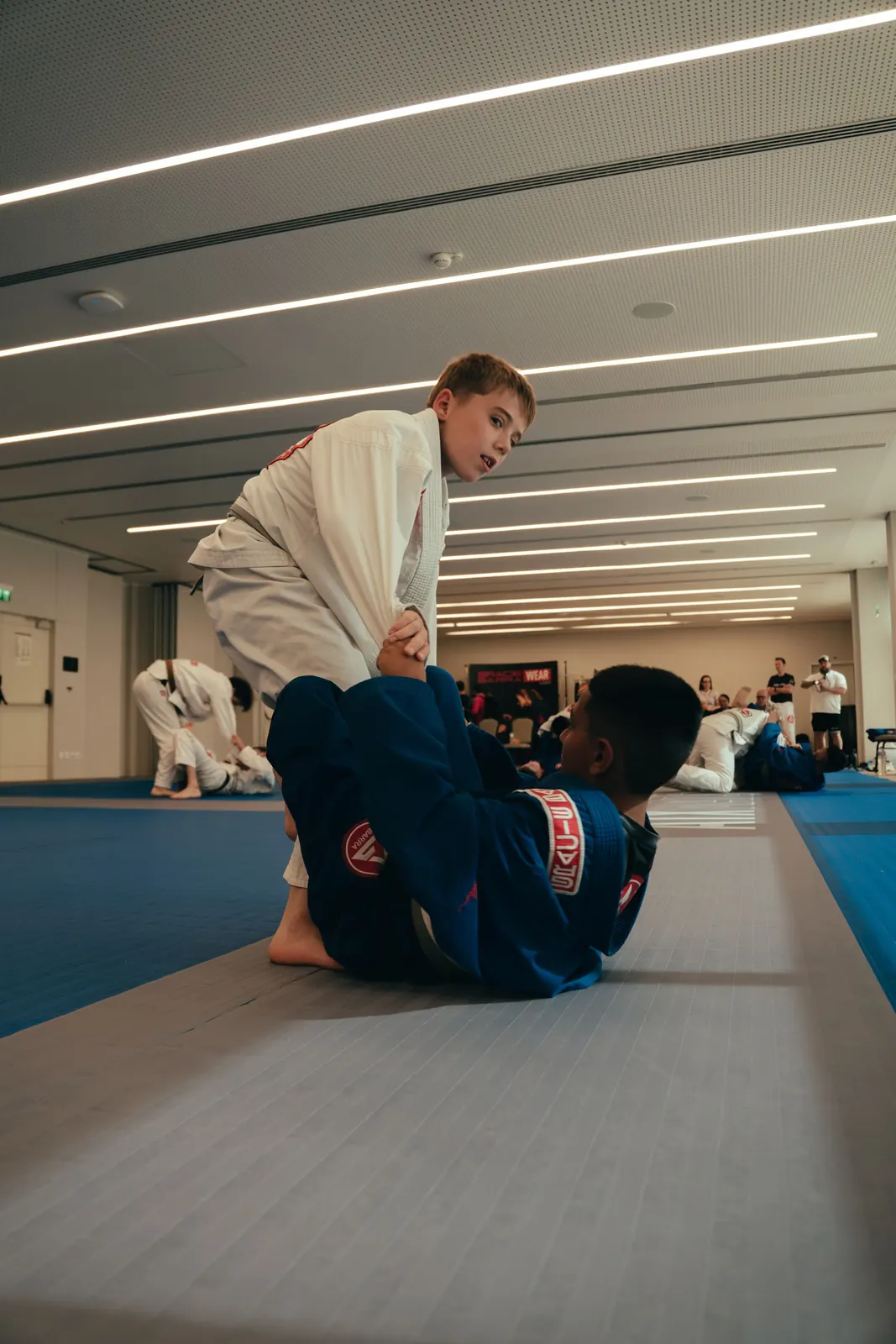 Two children practising Jiu-Jitsu together on blue mats